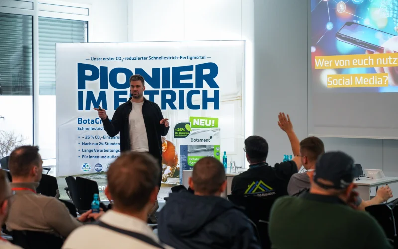 Mann hält einen Vortrag vor Menschen auf einer Messe der Firma Botament
