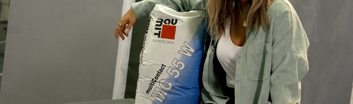 Frau sitzt mit einem Sack Baumit Multi Contact im Arm 