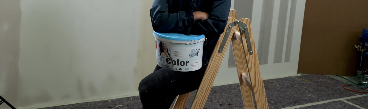 Frau sitzt auf einer Holztrittleiter mit einem Eimer IonitColor von baumit 