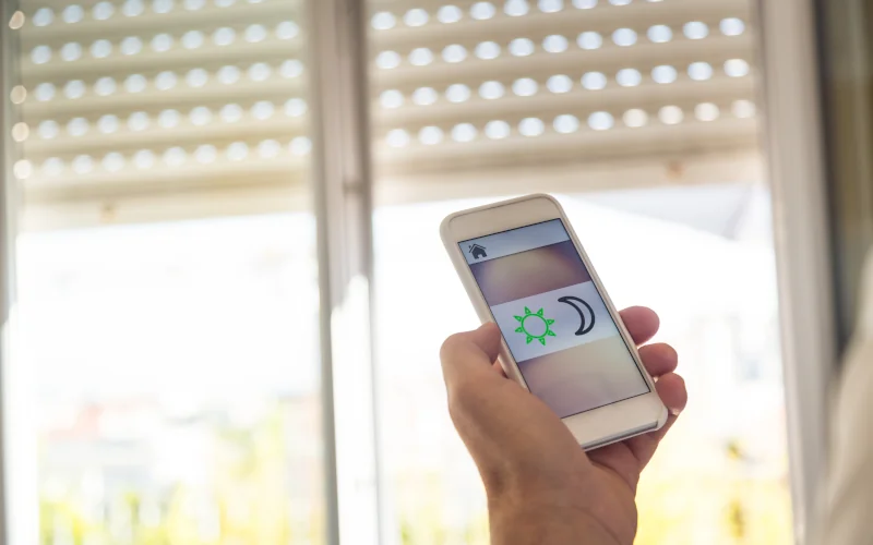 menschliche Hand steuert Rollläden über Smart Home