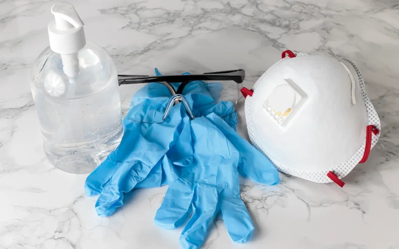 auf einer Marmorfläche liegen Reiniger, Handschuhe und Maske 