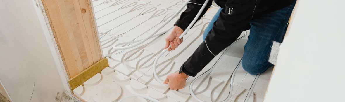 Handwerker baut Fußbodenheizung ein 