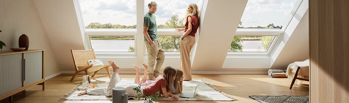 Eine Familie steht vor einer Fensterfront mit bodentiefer Verglasung in der Dachschräge