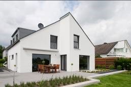 weißes modernes Einfamilienhaus mit Terrasse und Garten davor