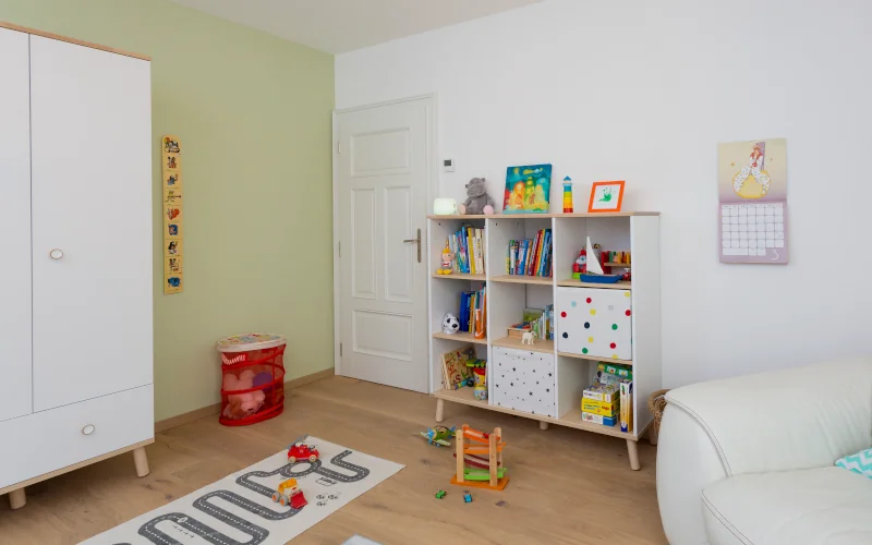 Kinderzimmer mit grünen und weißen Wänden und Spielzeug auf dem Boden liegend