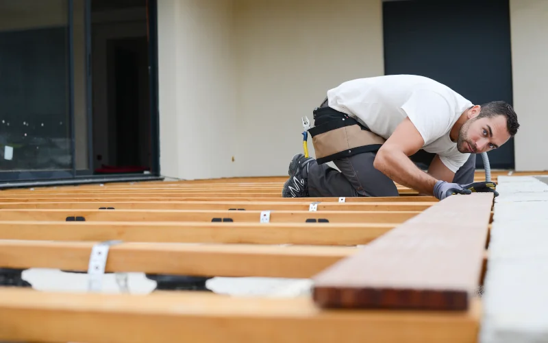 Handwerker verlegt Unterkonstruktion auf einem Terrassenboden