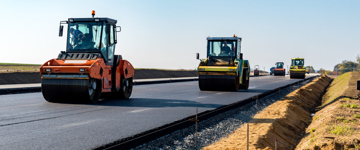 Straßenbau mit Asphaltwalzen auf neuer Straße.
