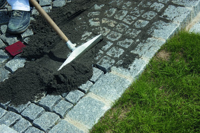 Erde wird zwischen Pflastersteinen verteilt