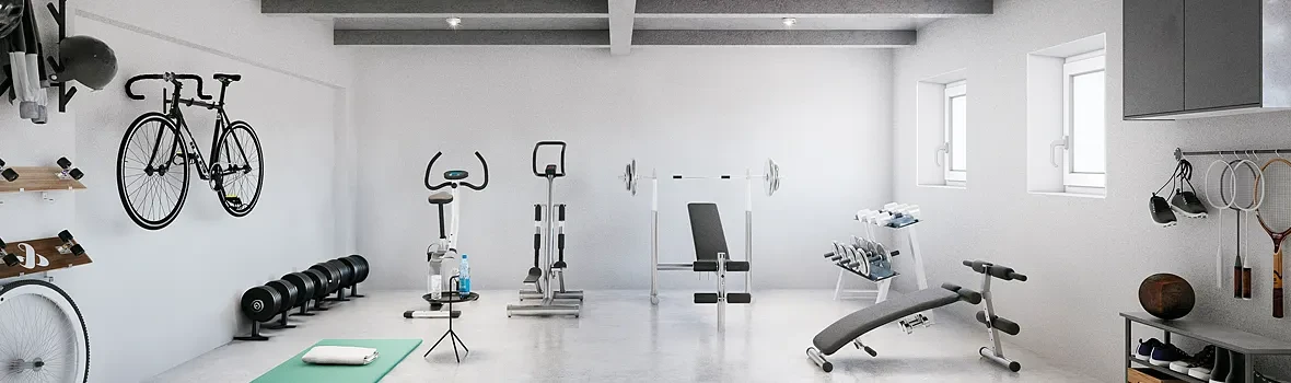 Ein Keller dient als Fitnessraum. Zu sehen  sind Cardiogeräte und Equipment für Kraftsport. Rechts oben sind zwei Kellerfenster.