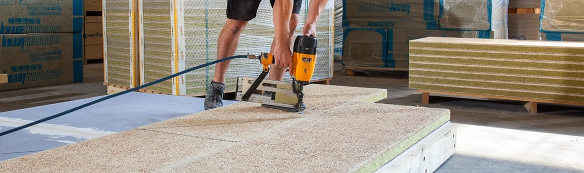 Handwerker befestigt Holzwolle Dämmplatten auf Unterkonstruktion