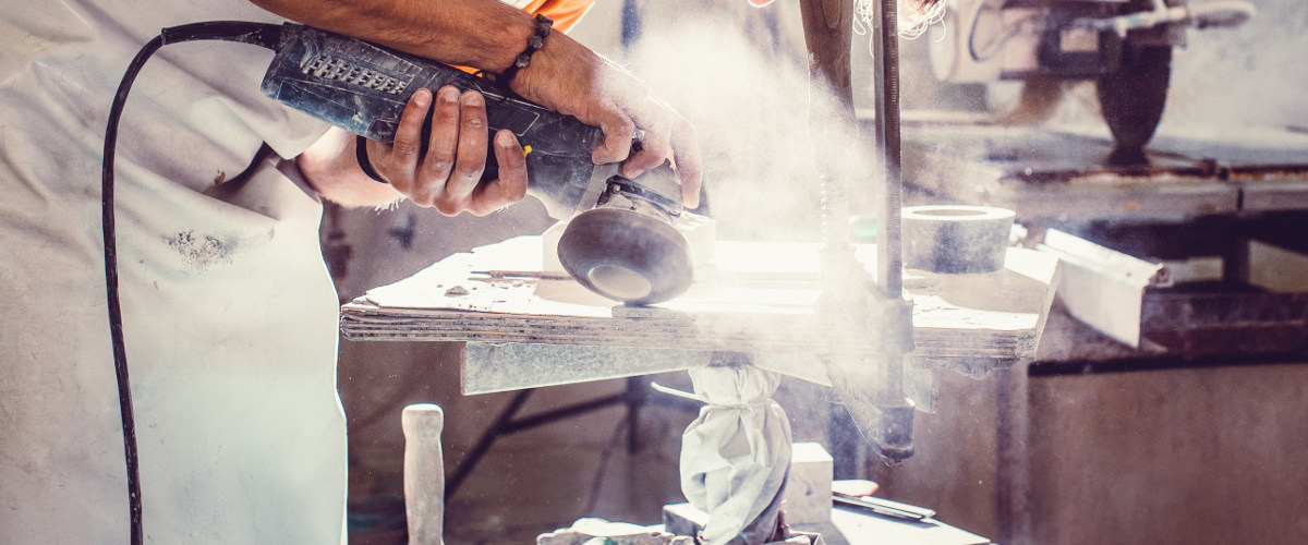Handwerker schleift mit einer Maschine und produziert viel Staub
