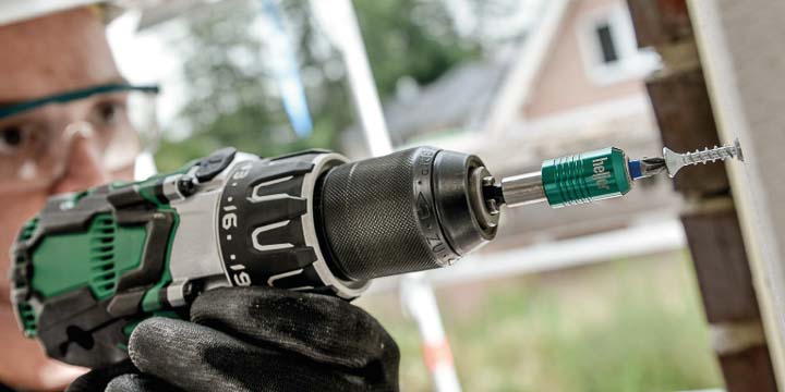 Handwerker mit Schutzausrüstung schraubt Schraube in eine Wand