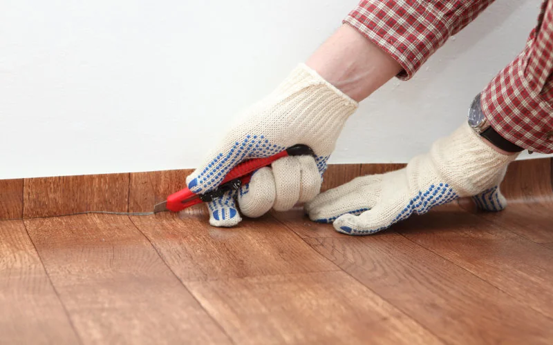 Handwerker schneidet Klebevinyl mit Cuttermesser zu 