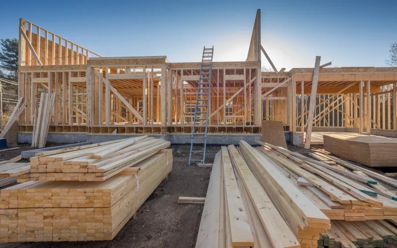 Haus im Hausbau mit Holzrahmenbauweise und viel Holz im Vordergrund liegend 