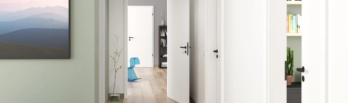 Flur einer Wohnung mit Holzboden und weißen geöffneten Zimmertüren mit schwarzen Griffen