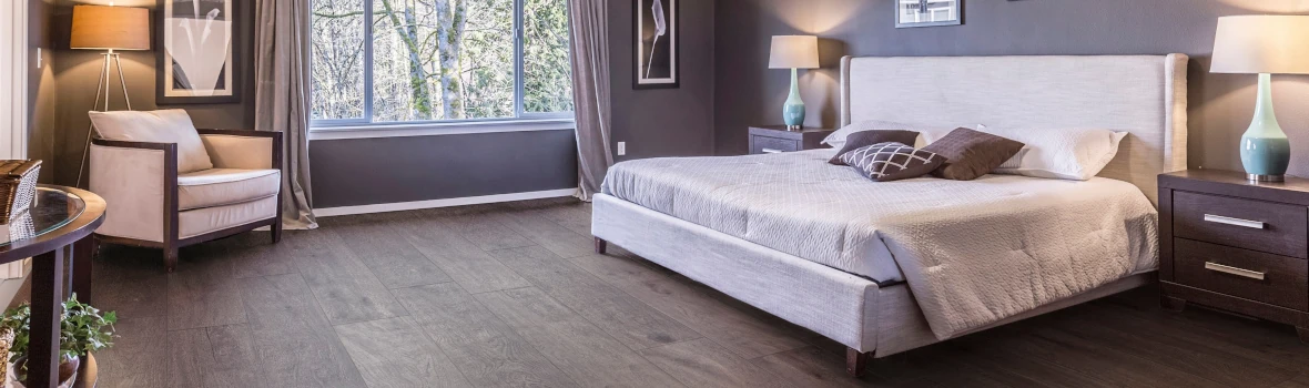 Elegantes Schlafzimmer mit großem Bett, gemütlichem Sessel, stilvollen Lampen und einem großen Fenster.