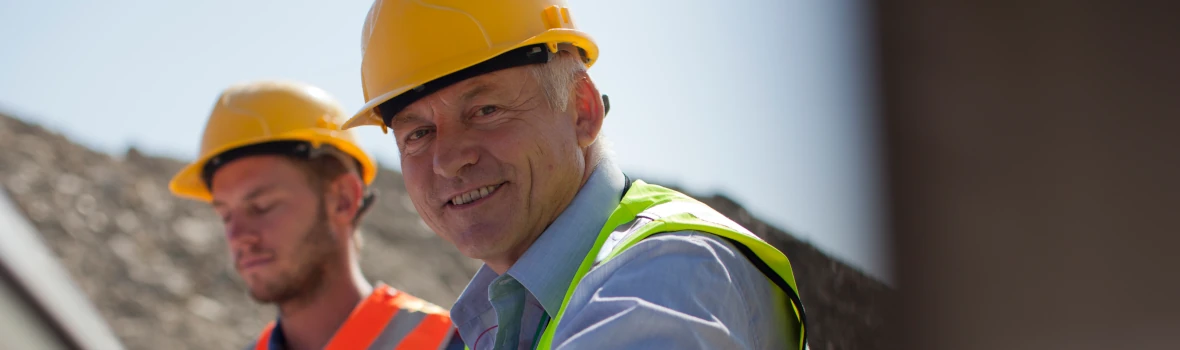 Zwei Männer mit Helm und Warnweste auf einer Baustelle
