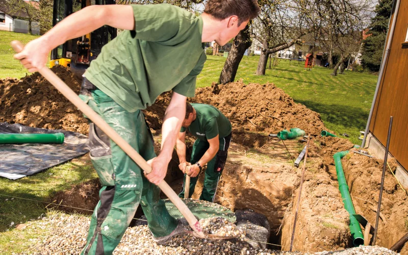 Handwerker buddeln einen Wassertank von Graf in die Erde ein