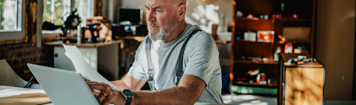 Der Handwerker arbeitet tagsüber am Laptop in der Werkstatt und überprüft Projektpläne