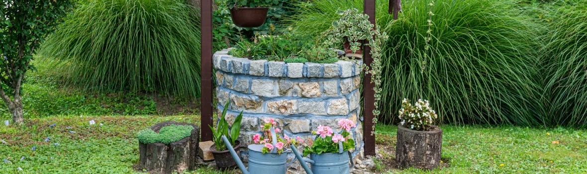 Zierbrunnen mit kleinem Dach und vielen Pflanzen und Dekostücken