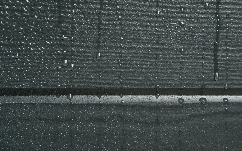 Hauswand mit schwarzen Fassadenplatten und tropfen darauf