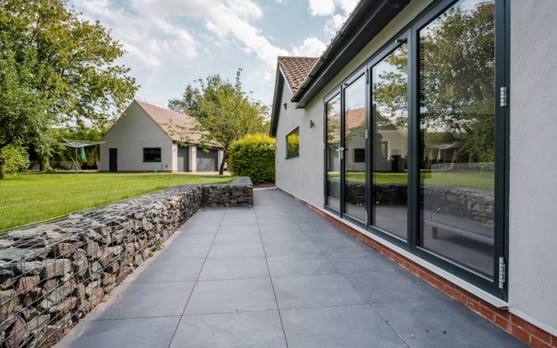 Terrasse am Haus mit Garten getrennt durch Steinmauer