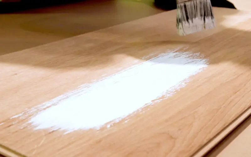 Holzplatte wird mit weißer Farbe gestrichen.