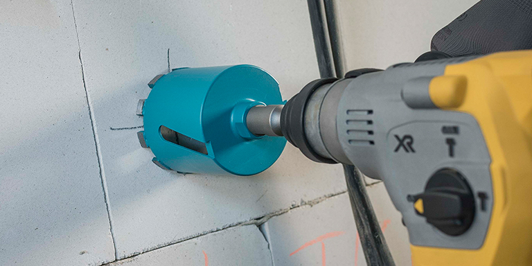 Loch wird mit Bohrmaschine mit speziellem Aufsatz in die Wand gebohrt 