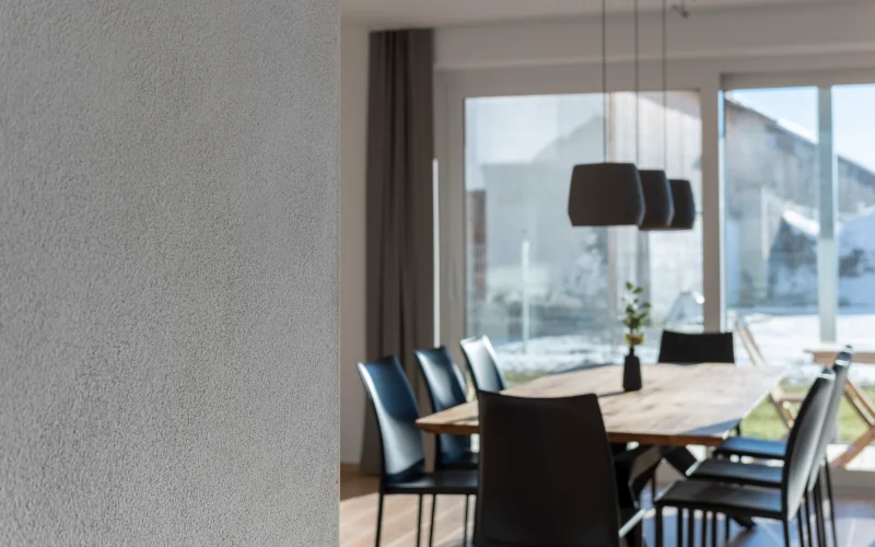 Esszimmer mit großer Lampe über dem Tisch und Blick in den Garten