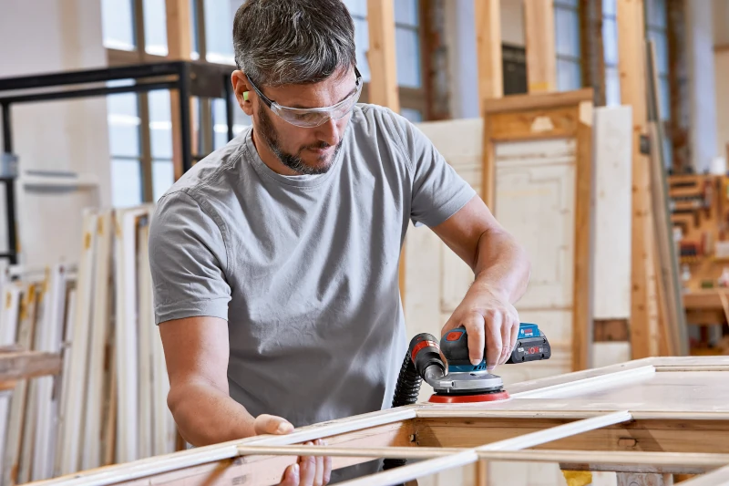 Handwerker schleift Holz in der Werkstatt mit Absaugung 