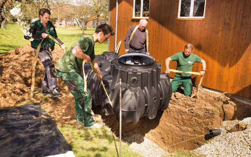 Handwerker lassen einen Wassertank von Graf in die Erde ein