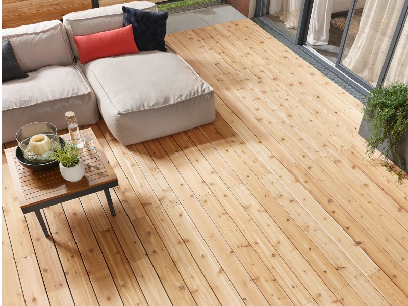 Eine kleine Terrasse mit Lärche-Terrassendielen. Es stehen bequeme Sitzmöbel auf der Terrasse.