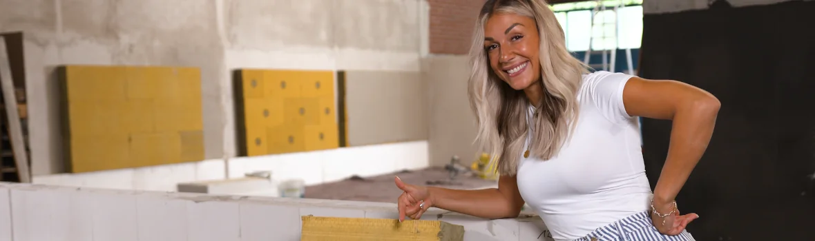 Frau steht auf einer Hausbaustelle neben einem Stapel Dämmplatten