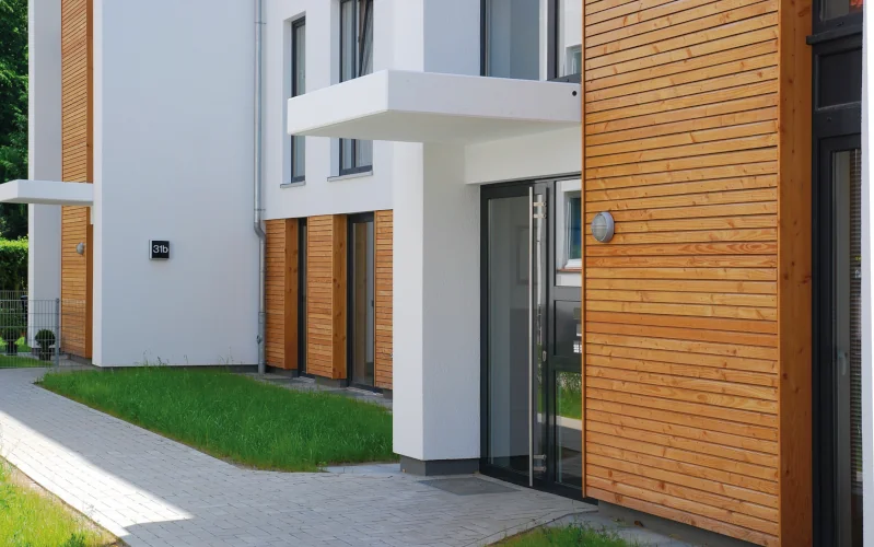 Reihenhaus mit weißer Putzfassade und Elementen aus Holz 