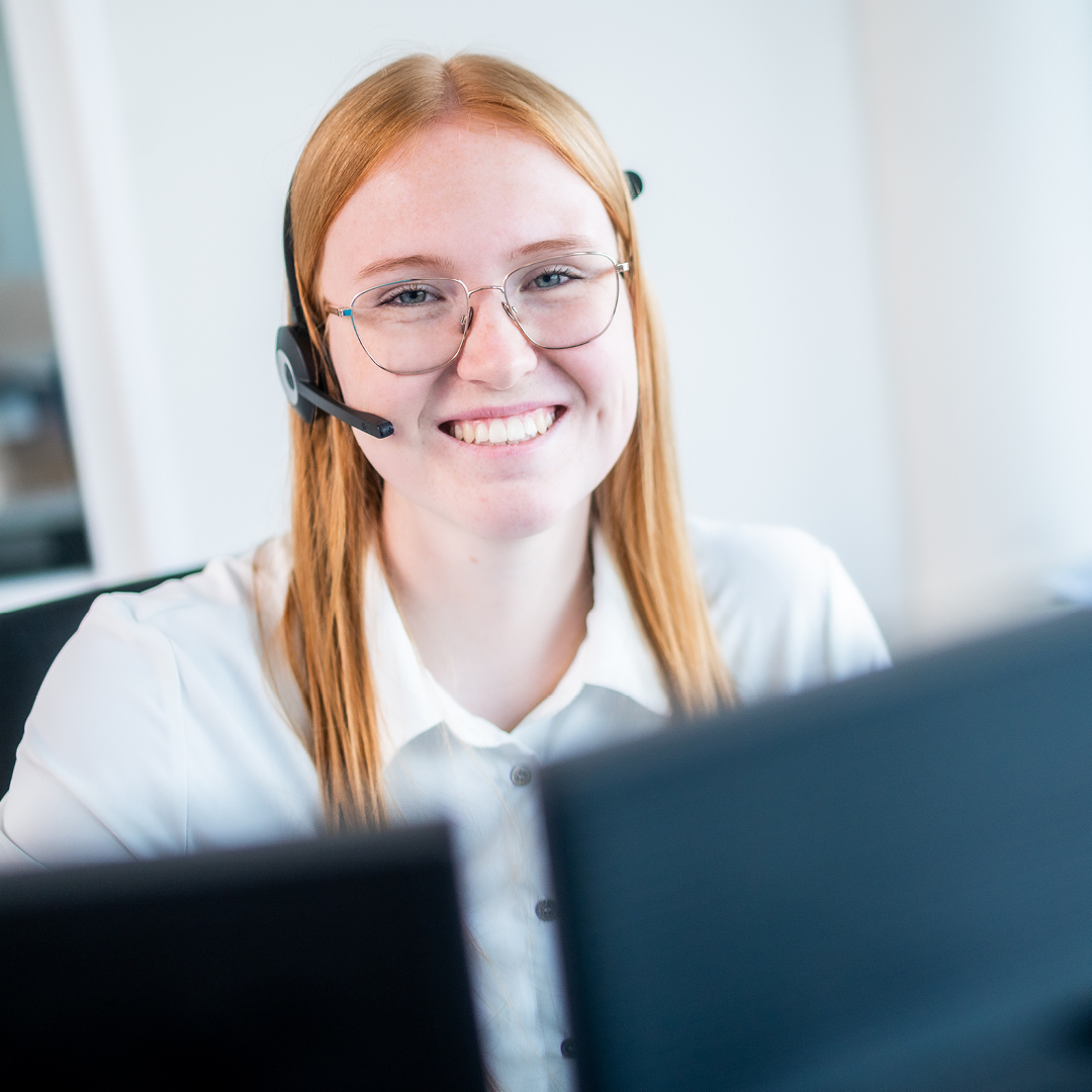 Frau mit Headset lächelt in die Kamera 
