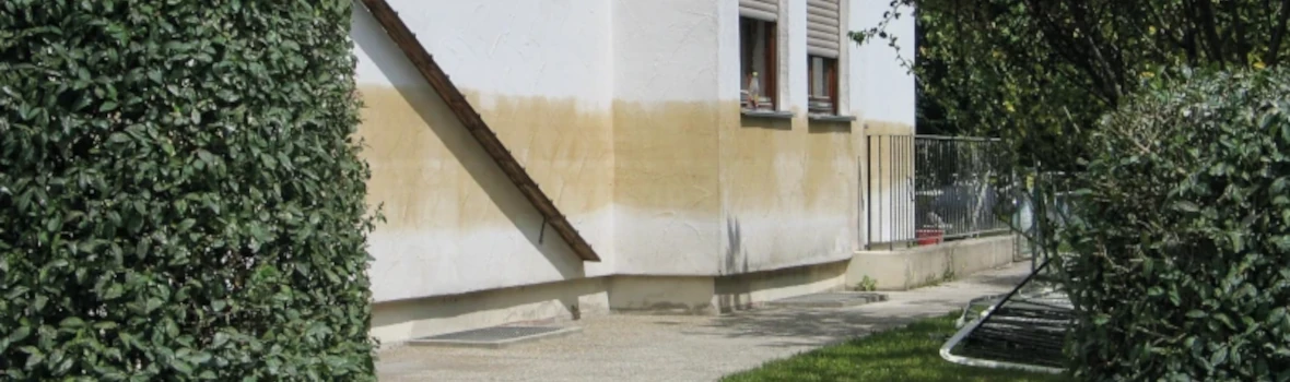 weiße sanierungsbedürftige Hausfassade mit Verfärbungen 