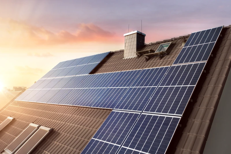 Hausdach mit großen Solarpaneelen bei Sonnenuntergang.