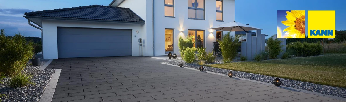 Eine grau gepflasterte Hauseinfahrt vor einer Garage mit dunklem Tor