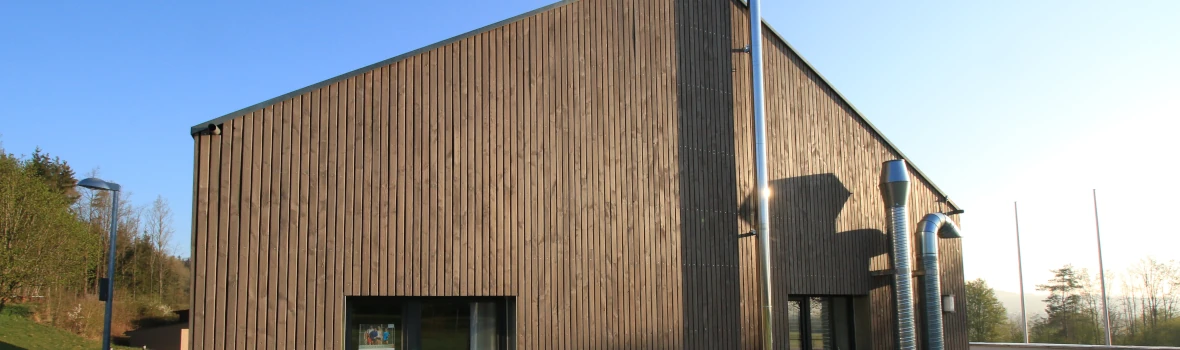 Blick auf ein Haus mit einer offenen senkrechten Holzfassade.