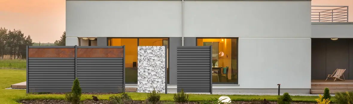 Ein anthrazit-farbender Sichtschutzzaun steht vor einem weiß-gräulichen Haus.