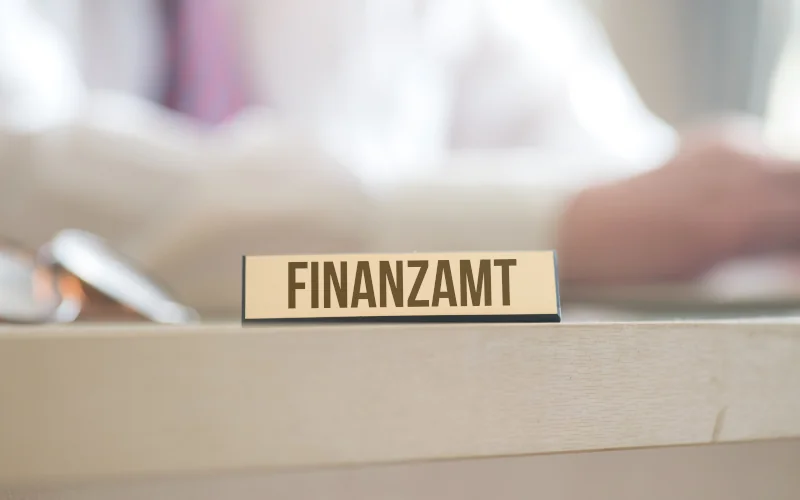 Schild mit der Aufschrift Finanzamt steht auf einem Schreibtisch