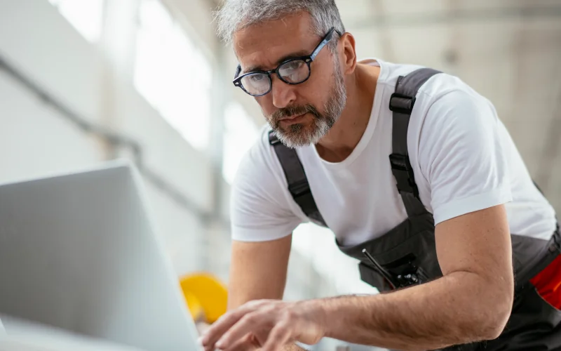 Handwerker mit Laptop in einer Werkstatt