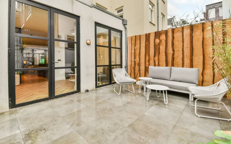 Terrasse mit Fliesenboden eines Wohnhauses mit schwarzen Glastüren