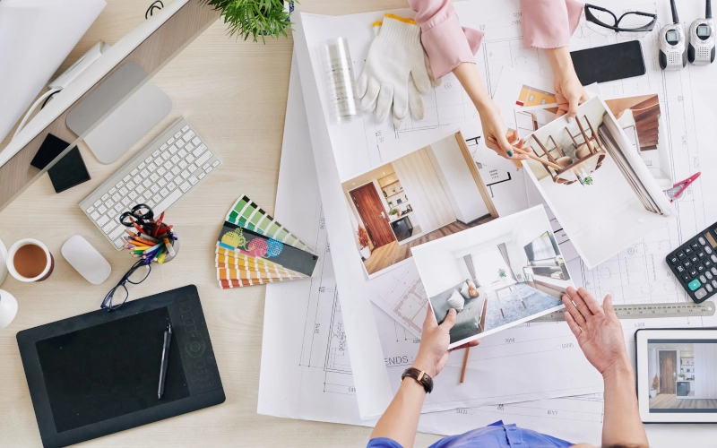 Hände von Innenarchitekten und Kunden, die 3D-Renderings von Raumgestaltung diskutieren