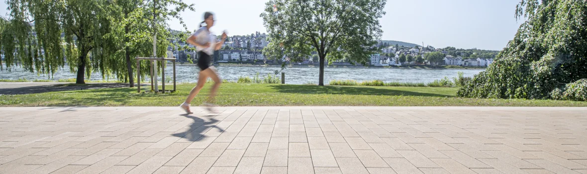 Frau joggt in einer Stadt am Wasser entlang 
