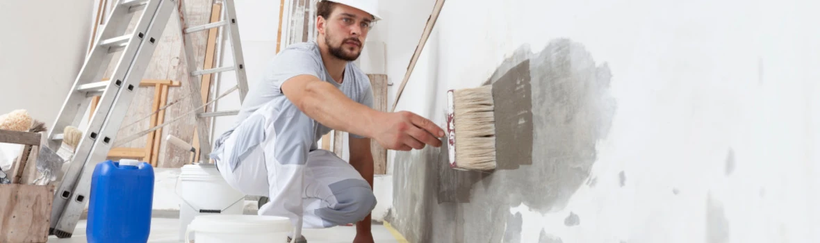 Ein Handwerker befeuchtet eine Wand. 