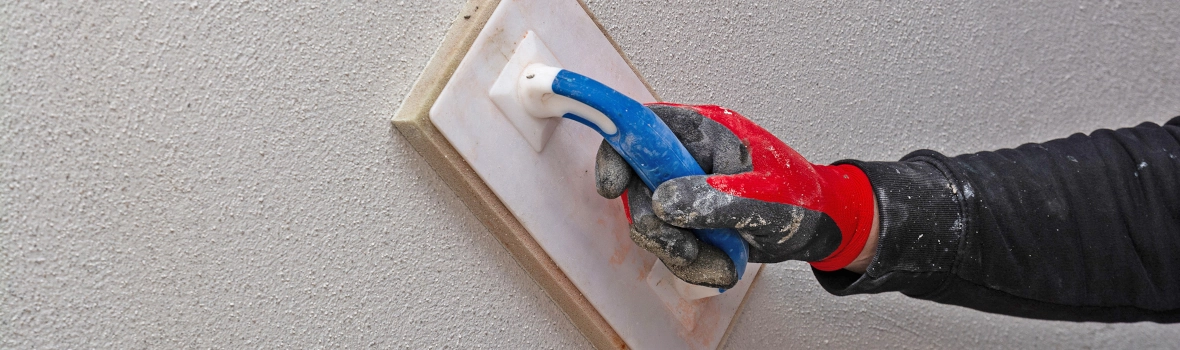 Hand mit Spachtel die den Sanierputz strukturiert und filzt