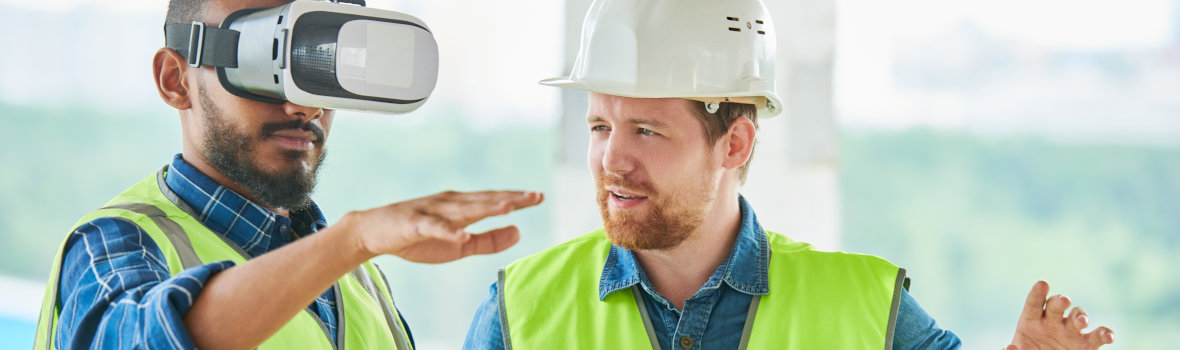 zwei Männer, einer davon mit aufgesetzter VR Brille auf einer Baustelle 
