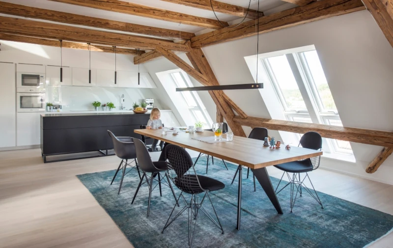 Modernes Esszimmer in Dachgeschosswohnung mit Holzbalken.