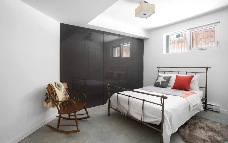 Schlafraum im Keller mit großem Kleiderschrank, Bett und Schaukelstuhl 